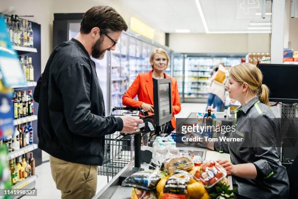 mature man paying for groceries at checkout - paar gruppierung stock-fotos und bilder