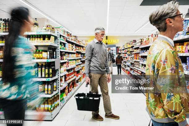 mature man shopping in supermarket - seniors shopping stock pictures, royalty-free photos & images