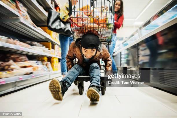 young boy riding bottom of shopping cart - shopping fun stock-fotos und bilder