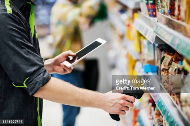 supermarket employee using tablet and bar code reader - contact list stockfoto's en -beelden