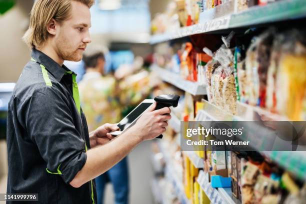 supermarket employee scanning food items - assistant foto e immagini stock