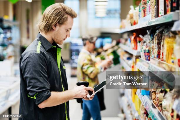 supermarket employee performing stock check - shop assistant stockfoto's en -beelden
