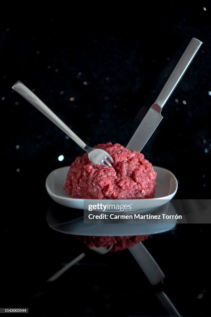 Plate with fresh raw ground beef isolated on white