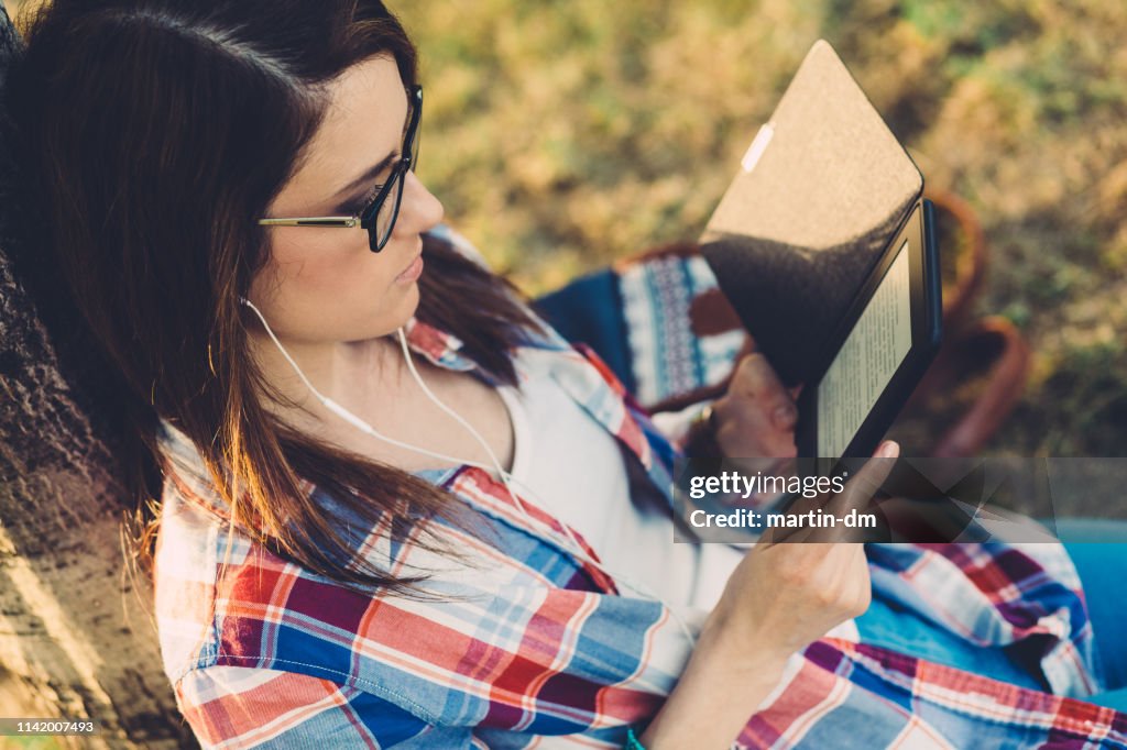 Woman in park reading an e-book