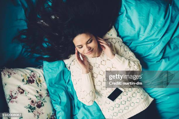 beautiful girl enjoying good music in bed - headphones eyes closed stock pictures, royalty-free photos & images