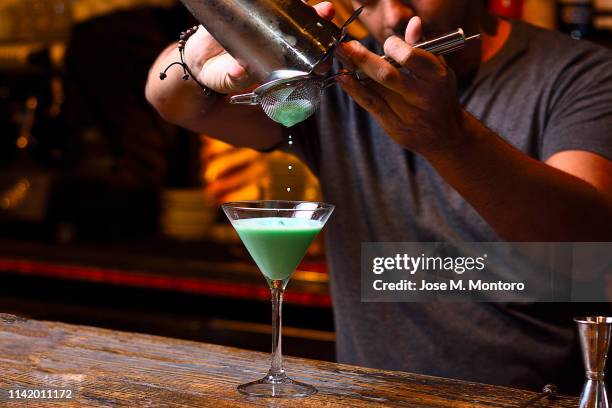bartender filtering the mix from de shaker - cocktail recipe stock pictures, royalty-free photos & images