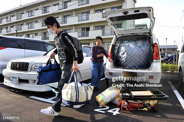 Family members unload their personal belongings from the trunk of their cars as they arrive at the new evacuation apartment on May 15, 2011 in...