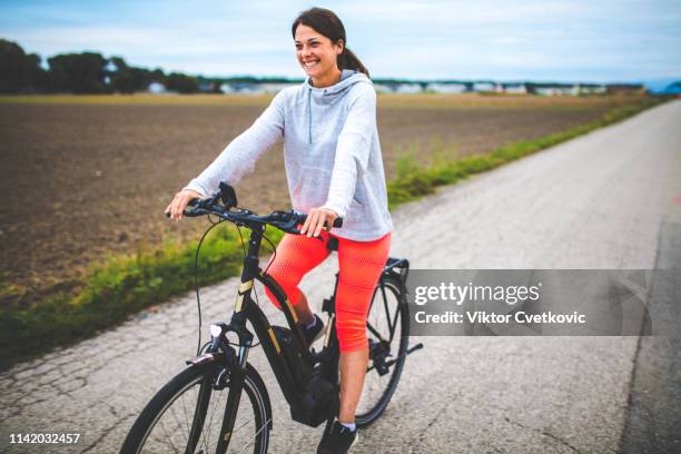 woman riding on her electric bicycle - e bike stock pictures, royalty-free photos & images