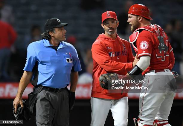 Umpire Phil Cuzzi and Kevan Smith of the Los Angeles Angels of Anaheim argue about the strike zone while Manager Brad Ausmus holds him back after...