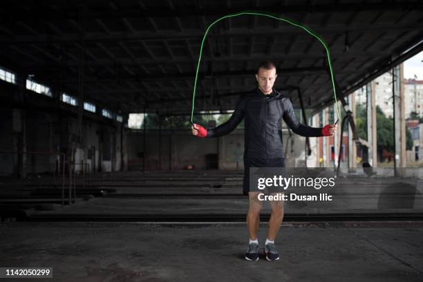 young man with jumping rope in garage - high contrast athlete stock pictures, royalty-free photos & images