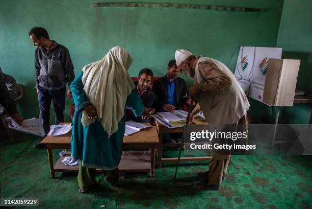 An elderly Kashmiri Muslim couple search their names in the voters list inside a polling station during the first phase of the elections of the lower...