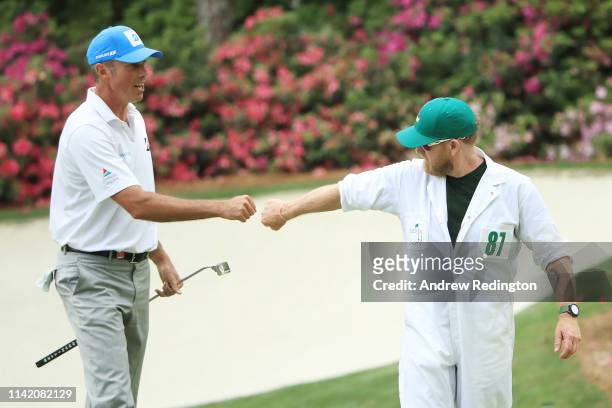 Matt Kuchar of the United States and caddie John Wood fist bump on the 13th green during the first round of the Masters at Augusta National Golf Club...