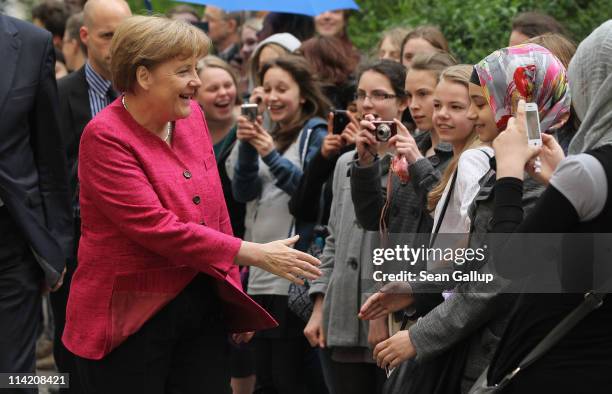 German Chancellor Angela Merkel greets students at the Sophie Scholl school during a visit on the fifth European Union school project day on May 16,...