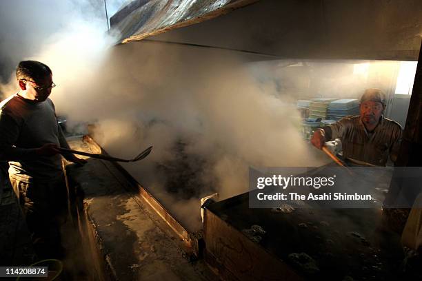 Workers remove the scum from boiled sea water to make sea salt on May 16, 2011 in Shiogama, Miyagi, Japan. The death toll has risen to over 15,000...