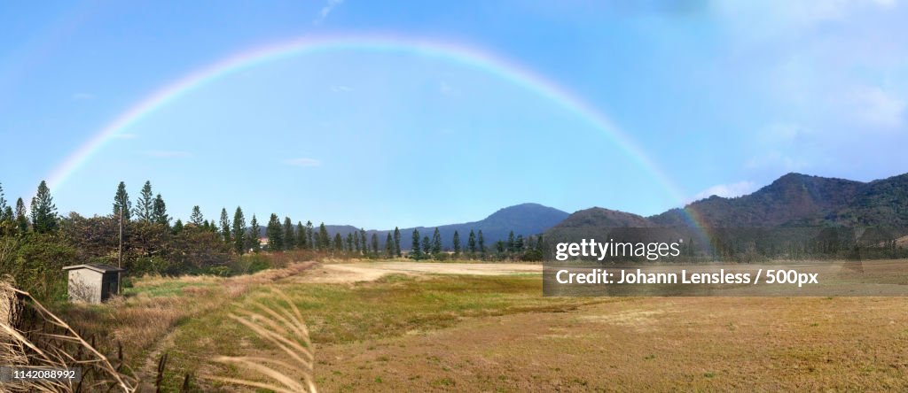 Landscape with rainbow under blue sky