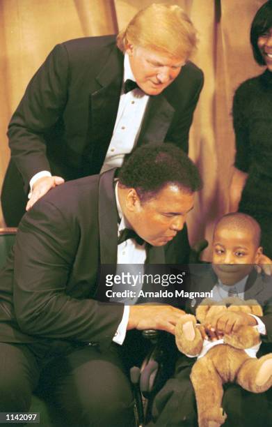 Legendary heavyweight boxing champ Muhammad Ali holds a UCP bear and kisses Yasin Shelton, a cerebal palsy patient as Donald Trump looks on March 14,...