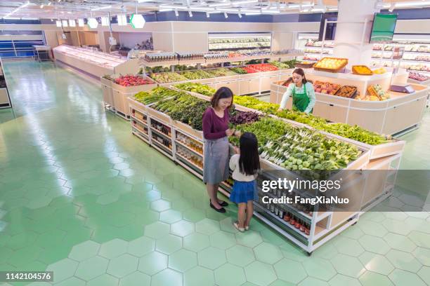 mère et descendant achetant des fruits ensemble - produce aisle photos et images de collection