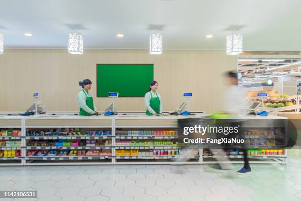 supermarkt personeel staat bij check-out balie - supermarket register stockfoto's en -beelden