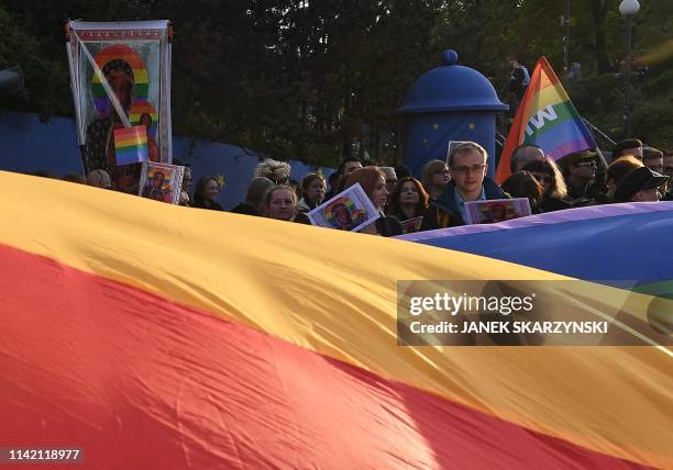 Protester hold rainbow flags and posters depicting the Virgin Mary with a rainbow halo during a rally for freedom of speech in downtown Warsaw on May...