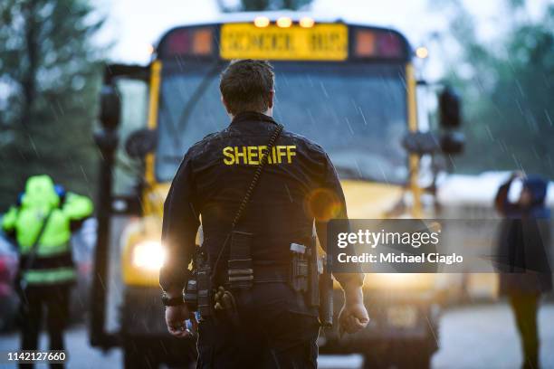 Sheriff's officer watches as students get off buses after being evacuated to the Recreation Center at Northridge after at least seven students were...