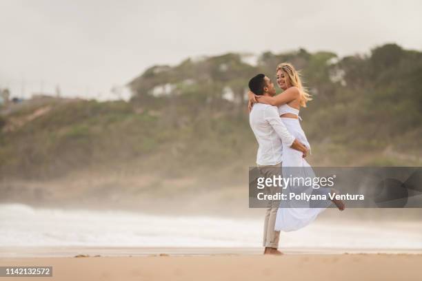 boda de elopement, novio abrazando y levantando novia - beach wedding fotografías e imágenes de stock