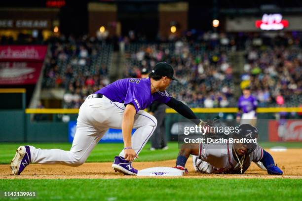 Josh Fuentes of the Colorado Rockies attempts to pick off Ronald Acuna Jr. #13 of the Atlanta Braves during a game at Coors Field on April 8, 2019 in...