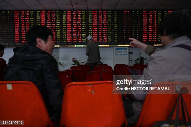 Investors monitor stock price movements at a securities company in Shanghai on May 8, 2019. - A red wave swept across Asia trading floors, as...