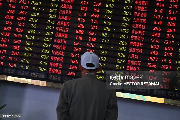 Investors monitor stock price movements at a securities company in Shanghai on May 8, 2019. - A red wave swept across Asia trading floors, as...
