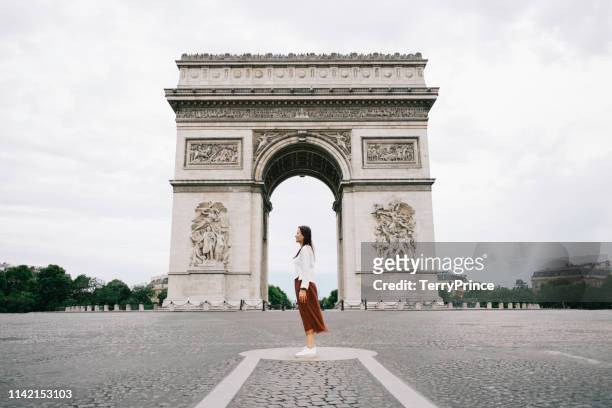 a woman standing in front of arc de triompheyoung in paris city. - arc de triomphe stock-fotos und bilder