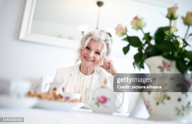 April 2019, Berlin: EXCLUSIVE - Helga Piur, actress, sits at a laid table in the dining room. Photo: Britta Pedersen/dpa-Zentralbild/ZB