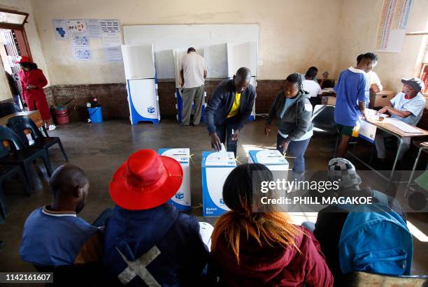 Various political party observors looks on as a man casts his vote at Rakgatla Secondary School polling station during South Africa's national and...