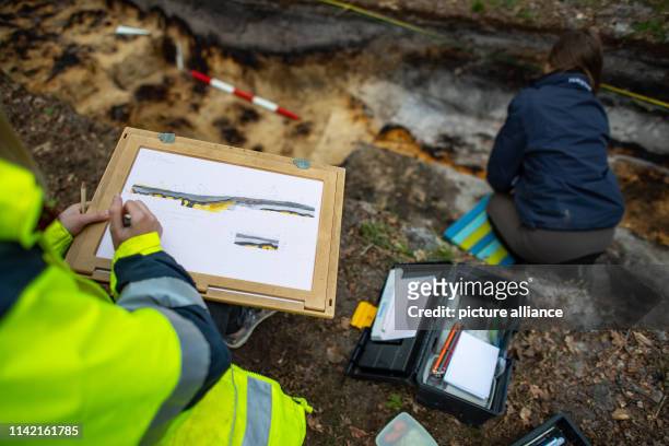 May 2019, North Rhine-Westphalia, Bielefeld: A trainee as an excavation technician of the LWL traces on a sheet of paper the uncovered spot of the...