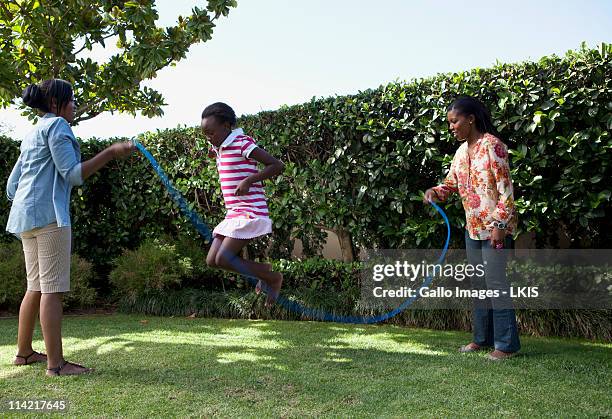 children playing jump rope in garden, johannesburg, south africa - johannesburg stockfoto's en -beelden