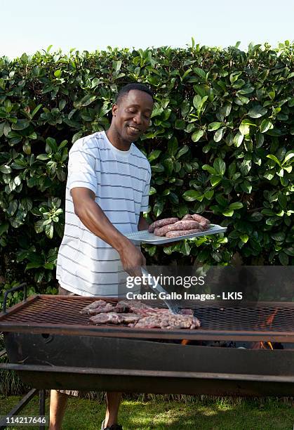 man braaing in garden, johannesburg, south africa - barbecue man stock pictures, royalty-free photos & images