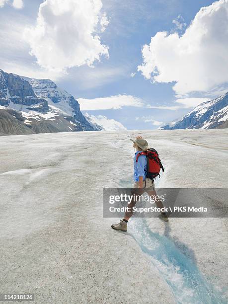 canada, alberta, jasper national park, hiker straddling glacial stream in columbia icefields - columbia icefield stock pictures, royalty-free photos & images