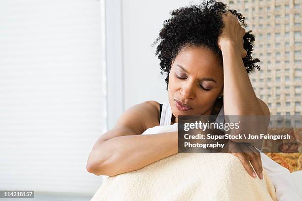 mid adult woman sitting on the bed and suffering from a headache - anxiété photos et images de collection