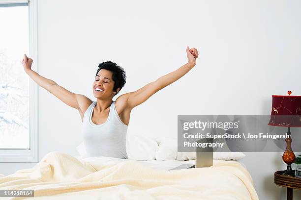 mid adult woman stretching on the bed - morning bed stretch fotografías e imágenes de stock