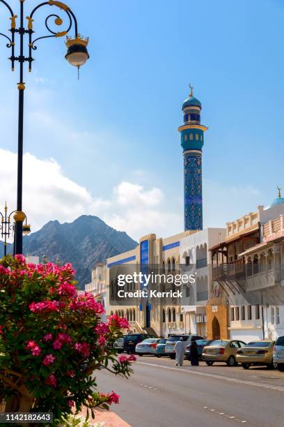 al bahri road im muscat - oman with flowers and a walkong senior couple. masjid al rasool mosque - maskat stock pictures, royalty-free photos & images