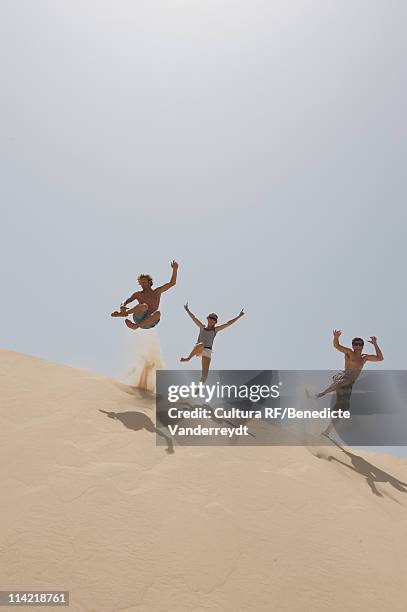 friends jumping over a big sand dune - tilt stock pictures, royalty-free photos & images