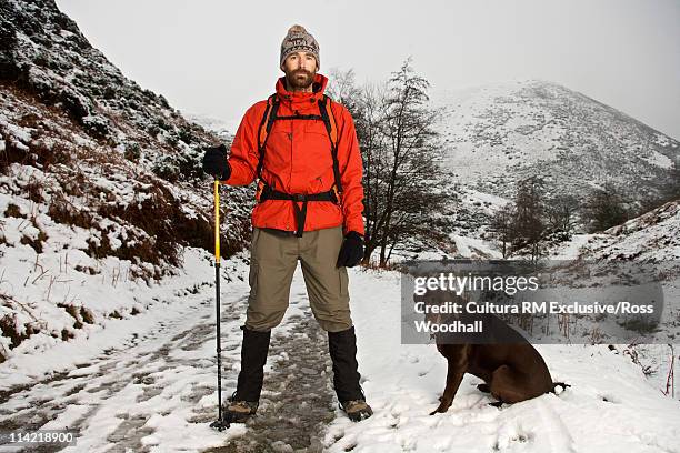 hill walker with dog - man standing in the snow stock-fotos und bilder