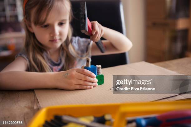 girl (6-7) hammering nails into wooden blocks - imitação de adultos - fotografias e filmes do acervo