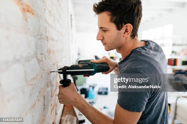 man met behulp van boormachine tijdens de wederopbouw van zijn appartement - drill stockfoto's en -beelden