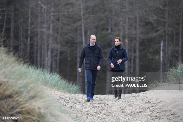 Britain's Prince William, Duke of Cambridge and his wife Britain's Catherine, Duchess of Cambridge walk along Newborough Beach on Anglesey, north...