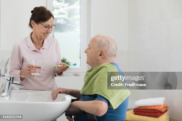 caregiver with senior man in bathroom - bathroom senior stock pictures, royalty-free photos & images