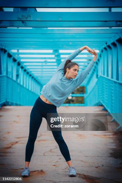 female runner doing core side bend outdoors - blue leggings stock pictures, royalty-free photos & images