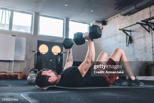 kaukasischer mann macht übungen für die brust mit dumbbels - bench press stock-fotos und bilder