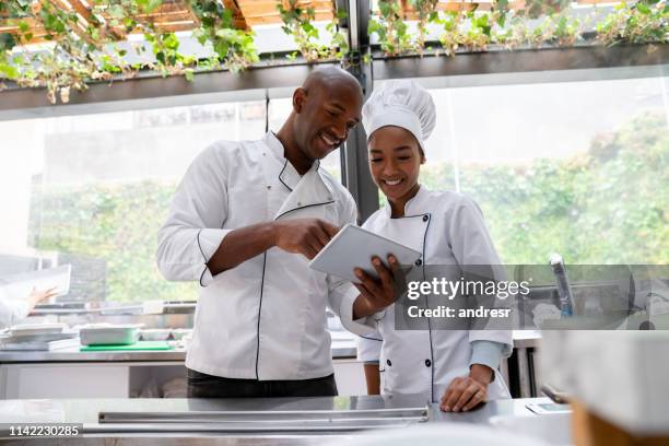 african american chefs at a restaurant looking at the menu on a digital tablet - black chef stock pictures, royalty-free photos & images