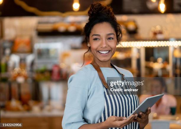 beautiful waitress working at a restaurant using a tablet computer - black apron stock pictures, royalty-free photos & images