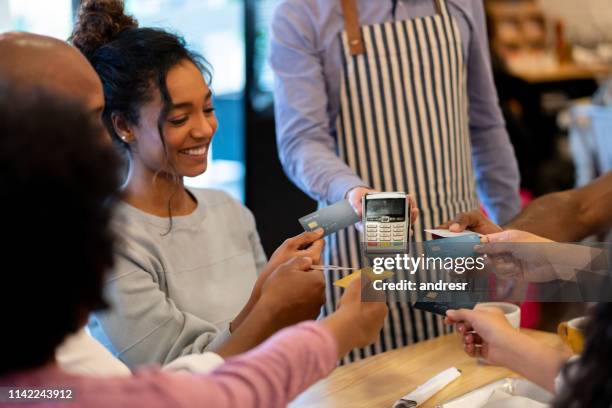 group of friends paying with a credit card at a restaurant and splitting the bill - division stock pictures, royalty-free photos & images