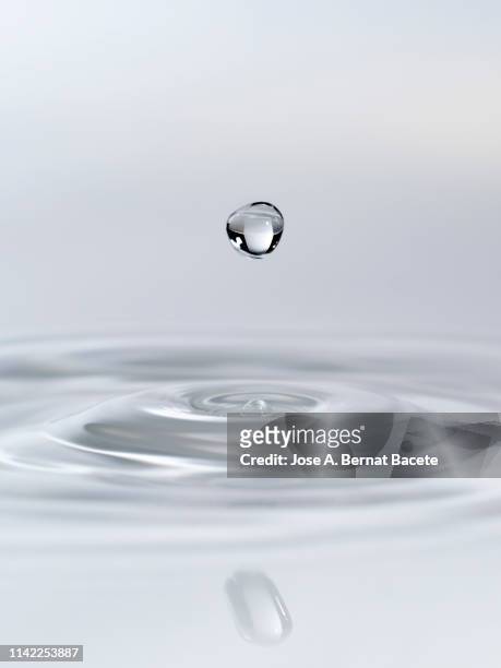 drop suspended in the air, falling down on a water surface that forms figures and abstract forms, on a white background. - circle water ストックフォトと画像